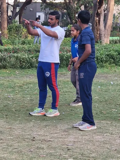 Instructing a young athlete on the finer points of an agility drill. Coaching is about clear communication and attention to detail.
