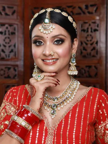 This bride is wearing a bright red lehenga. We opted for a classic winged eyeliner and glowing skin, accessorized with a traditional sheeshpatti.