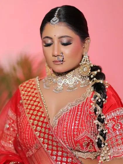 The complete look against a soft pink background. The red lehenga stands out beautifully, and the makeup perfectly complements the entire aesthetic.
