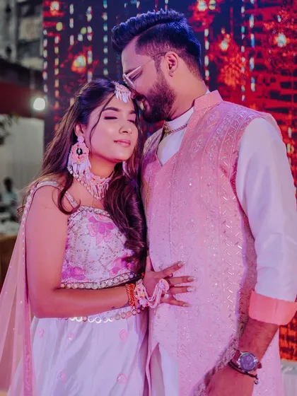 A Haldi bride and groom, her hair in a simple half-updo with soft waves.