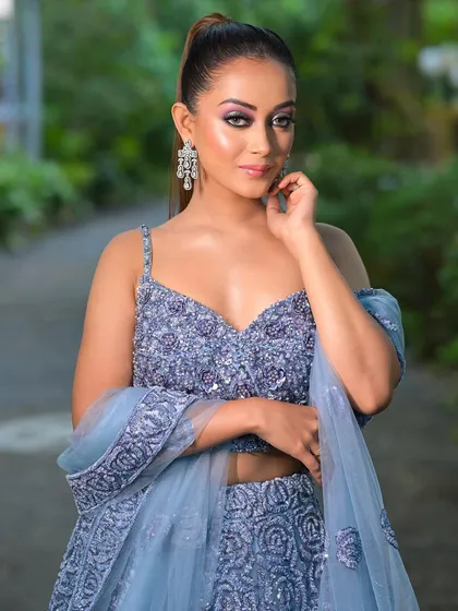 An outdoor shot of the dusty blue lehenga. The high ponytail and glamorous makeup show how this outfit can be styled for a modern, chic look.
