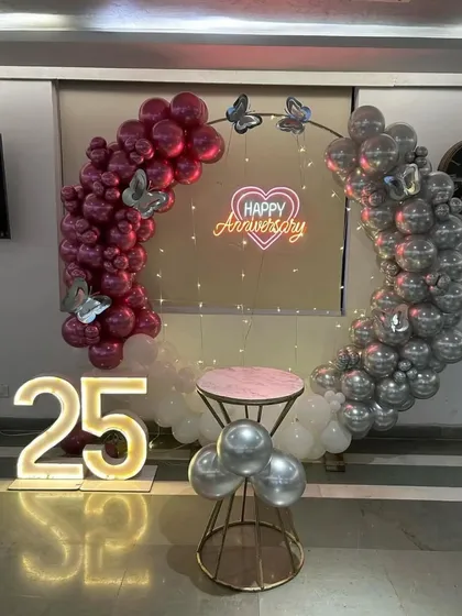 A centered view of the silver jubilee decoration, highlighting the butterfly accents on the balloon arch and the glowing "Happy Anniversary" sign.