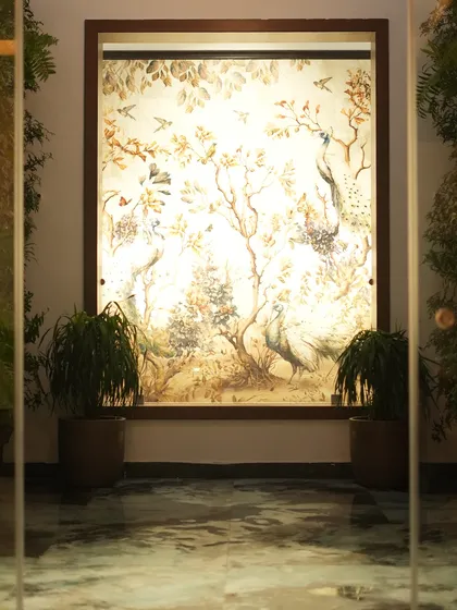 Another perspective of the grand mural and plant installation, viewed through glass doors, which adds depth and frames the artwork beautifully.