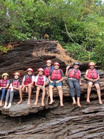 Campers take a rest on unique rock formations along the riverbank in Dandeli, a scenic break during the rafting expedition.