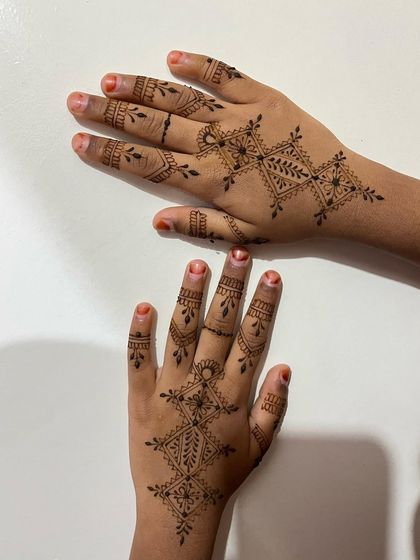 The completed geometric design on a child's hands, showing the playful yet intricate pattern.