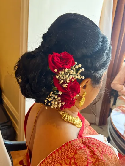 A hairstyle can complete the entire look. I created this beautiful messy bun using the client's own hair and adorned it with fresh red roses and baby's breath for a romantic and traditional touch.