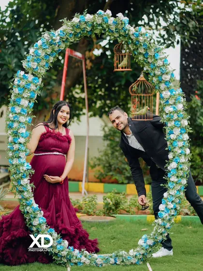 A playful couple's portrait framed by a large circular arch of blue and white flowers.