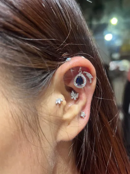 A bold and beautiful ear stack featuring a deep blue teardrop hanging, butterfly studs, and a curved bar for a touch of modern edge.
