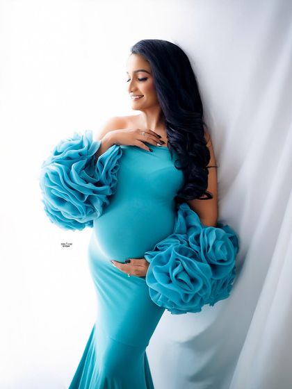 A soft and gentle portrait by the window. The natural light beautifully illuminates this mamma in her aqua blue gown, creating a truly angelic look.