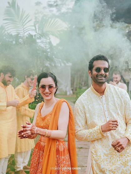 Eli and Suman making a cool entrance with color smoke. This adds a modern, fun twist to their traditional Haldi celebration.