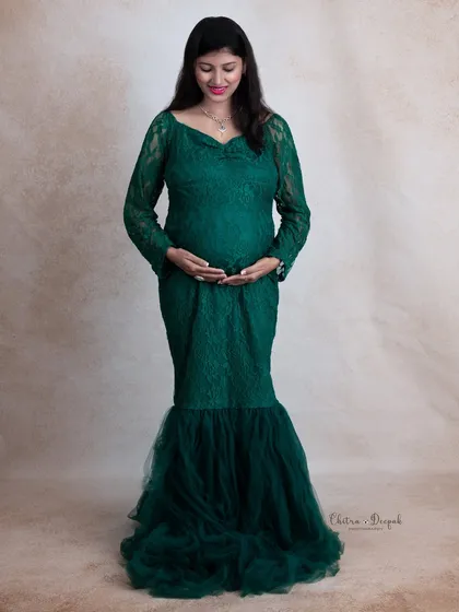 A full-length view of our gorgeous emerald green lace gown. This classic standing pose is perfect for showcasing both the dress and the beautiful baby bump.