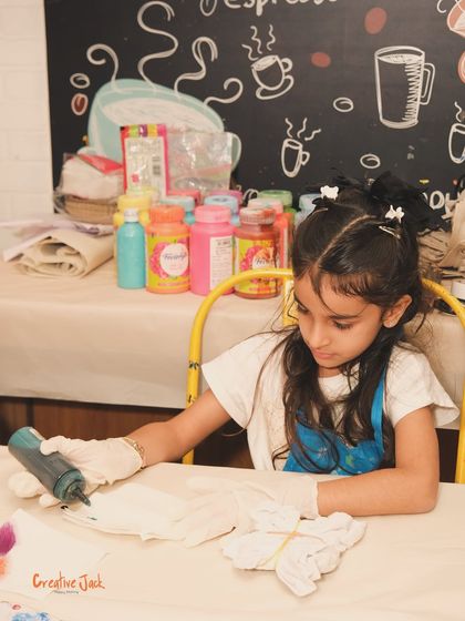 A young artist works on her tie-dye creation, surrounded by bottles of colorful paint. I ensure a safe and fun environment for all creative explorations.