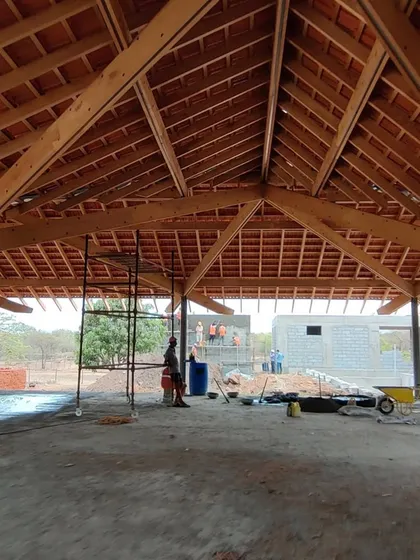 The expansive interior of the Alibaug residence, defined by its impressive exposed timber roof structure. This space is designed to feel open and airy, sheltered by a canopy of wood and tile.