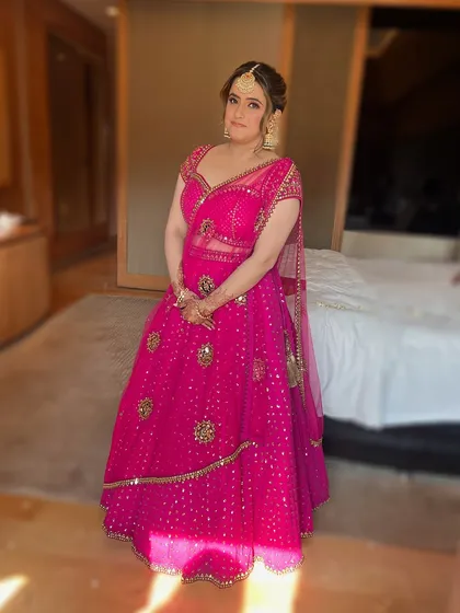 A full-length shot of the bride at her Mehendi, looking radiant in a vibrant pink lehenga.