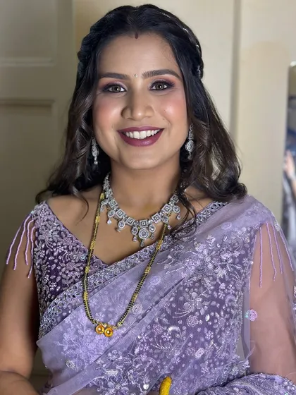 A happy bride ready for her reception in a lavender saree, with her hair in soft waves.
