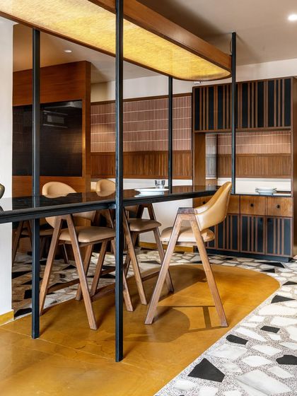 The Chandkheda outlet of Eat Punjab features a central hanging communal table, a design we adapted for its cozier layout. The space is defined by a striking black and white terrazzo floor, high-back wooden chairs, and a fabric light fixture that anchors the entire dining experience.
