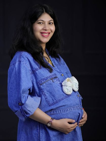 A playful and cute way to announce the baby's arrival. A tiny pair of white baby shoes are tucked into the pocket of this mom-to-be's denim shirt.