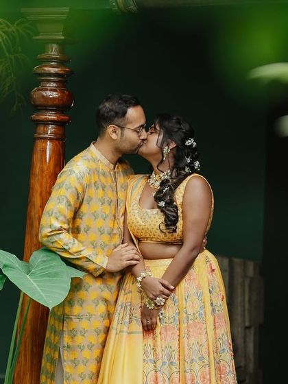 A sweet, intimate kiss shared by the couple amidst the fun and chaos of their Haldi ceremony.