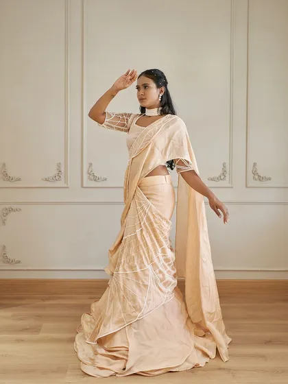 Introducing 'Luster', a modern draped saree gown in a delicate peach color. The wired ruffle detailing adds a contemporary twist to a classic silhouette.