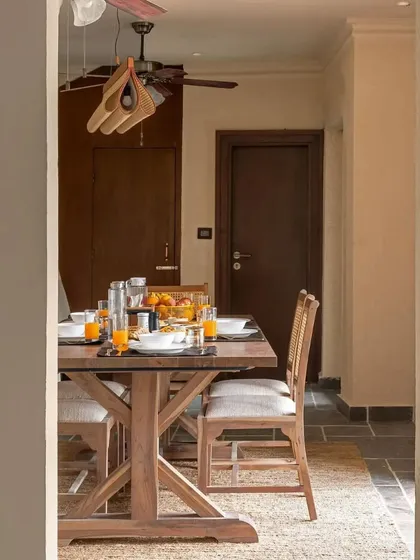 The breakfast table at Buransh Terraces, a cozy and informal spot to start the day. The design uses simple, well-crafted wooden furniture that complements the home's rustic-modern aesthetic.