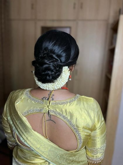 A classic, elegant low bun adorned with malli poo. This hairstyle is a timeless choice for bridesmaids or for a simple, traditional event.