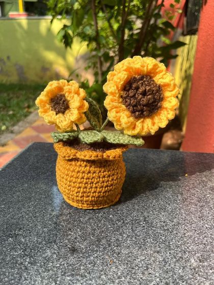A close-up of our adorable potted crochet sunflowers. We designed this piece with two flowers, one big and one small, to look like a real growing plant.