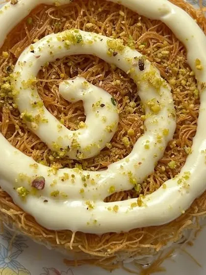 A close-up of our exquisite Turkish Cream Kunafa. This dessert features delicate, crispy kataifi pastry layered with a rich, creamy filling and garnished with pistachios. It's a sweet finale that perfectly balances texture and taste.