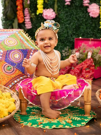 This happy little Krishna is ready for the Janmashtami festivities. The colorful fabrics and traditional props complete this adorable themed look.