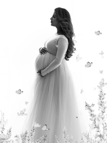 A dreamy, high-key black and white portrait. The soft light and whimsical butterfly details create an ethereal and artistic feel.