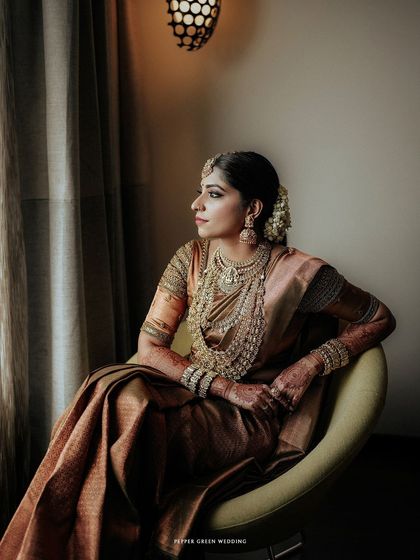 A pensive portrait of the bride, Sradha, seated by a window. The soft, natural light and her elegant pose create a timeless and artistic image.