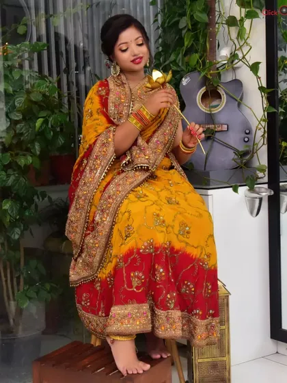 A full-length shot showing the complete traditional outfit. The setting includes subtle props like a guitar and plants to create a relaxed, indoor lifestyle feel.