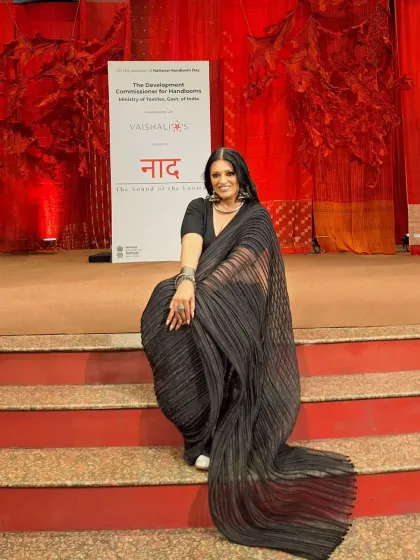 A dramatic pose on the steps of the event stage. The long pallu of the pleated saree creates beautiful lines and movement.