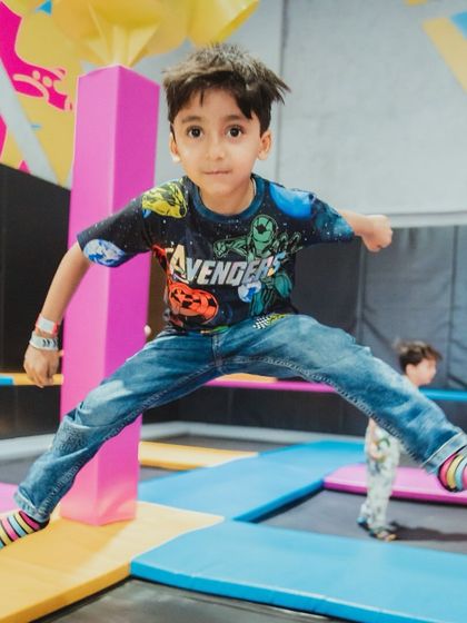 A young boy, dressed in an Avengers t-shirt, jumping for joy on the trampolines. His energy and excitement are contagious!