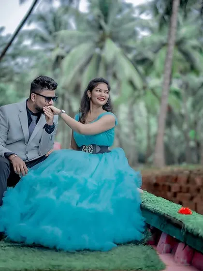 A romantic pre-wedding moment on a boat. The groom-to-be kisses his partner's hand, who looks radiant in a sky-blue ruffled gown.