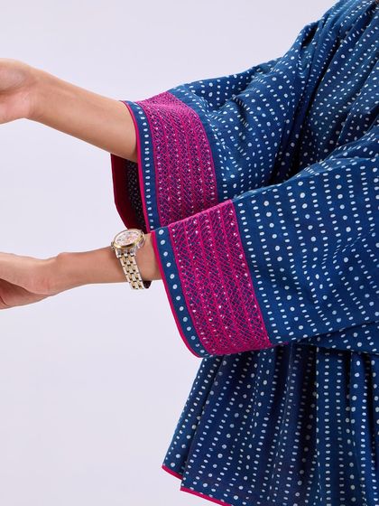 A detail of the sleeve on our Chaaya top, featuring a pop of pink embroidery. These small highlights of color add a playful touch to the deep indigo prints.