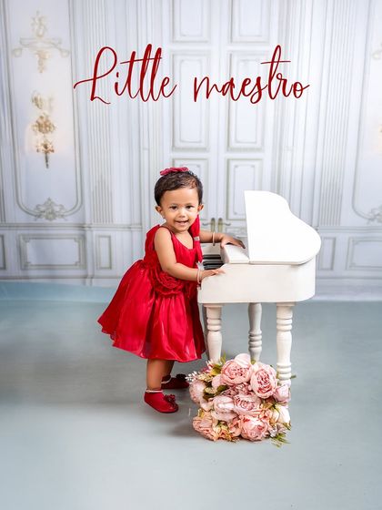 A little maestro in a stunning red dress. The contrast of the red against the elegant white piano and backdrop makes for a striking and beautiful portrait.