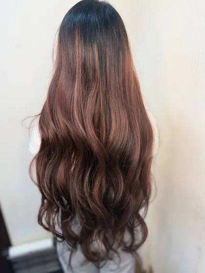 A stunning example of a brunette balayage. The subtle, warm highlights add dimension and shine to her very long hair.