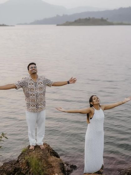 A joyful moment of freedom, with the couple spreading their arms wide by the lakeside, embracing the beauty of the natural landscape.