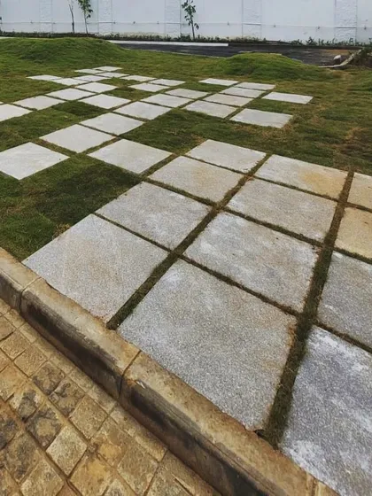 A playful 'Tetris' pattern of stone pavers is set into a grassy mound at an industrial site. This design element adds a touch of whimsy and creativity to a typically utilitarian environment.