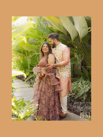 A beautiful couple portrait set against lush greenery. The groom's embrace and their happy expressions make this a warm and romantic shot, perfect for remembering their special day.