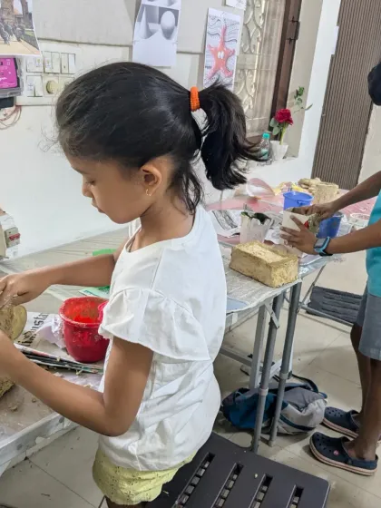 A candid shot of a young student focused on shaping her papermache project. This is where the hands-on learning happens.
