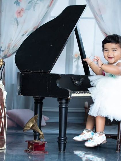 This little girl is having a great time at the piano, surrounded by vintage props like a gramophone and an old telephone.