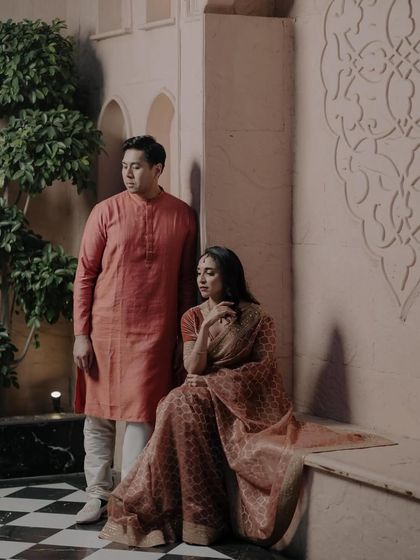 A beautifully composed pre-wedding shot in traditional attire. The makeup is elegant and subtle, complementing the rich colors of their outfits.