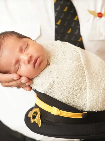 A pilot's precious cargo. This heartwarming photo shows a newborn being held in a pilot's hat, a wonderful tribute to a parent's career.