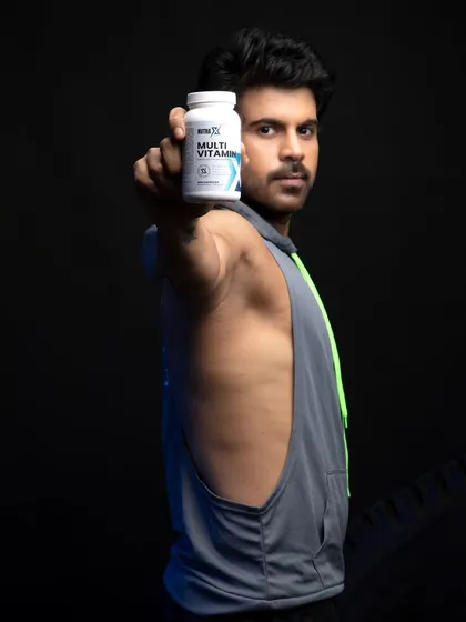 A direct, product-forward shot designed for clear communication. The model holds the multivitamin bottle towards the lens, making the label and branding the undeniable hero of the image. This style is essential for product detail pages and catalog photography where clarity is key.