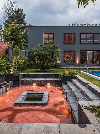 This is our award-winning project, 'The Grey Grotto', a contemporary farmhouse on the outskirts of Bengaluru. The design seamlessly integrates the home with its landscape, featuring a sunken lounge, a swimming pool, and expansive green spaces for true indoor-outdoor living.