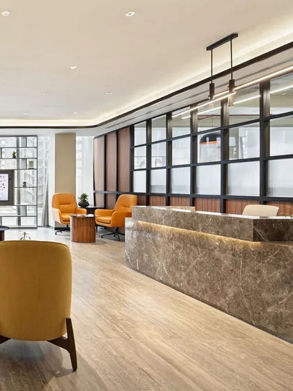 The reception area of a corporate office, where a monolithic marble desk and warm wood paneling create a sophisticated and welcoming entry point.