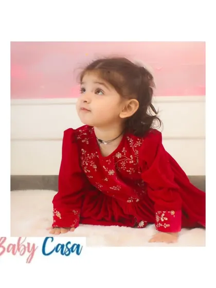 A close-up of the delicate embroidery on our red velvet dress. We believe the details make the outfit, and we pour our hearts into every stitch to create something truly special for your child.