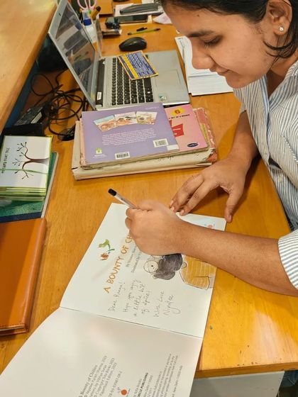 Another view of the illustrator signing a book, showcasing the personalized touch.