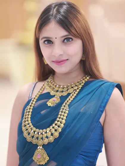 A direct-to-camera portrait, perfect for showcasing the intricate details of the layered gold necklaces.